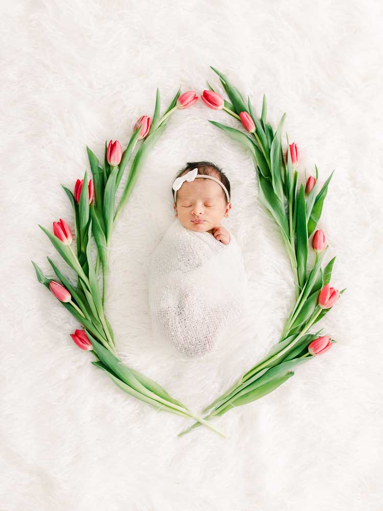 Newborn baby girl surrounded with flowers, In-home newborn photography photo inspiration by Juliana Kaderbek Photography, Cleveland Newborn Photographer
