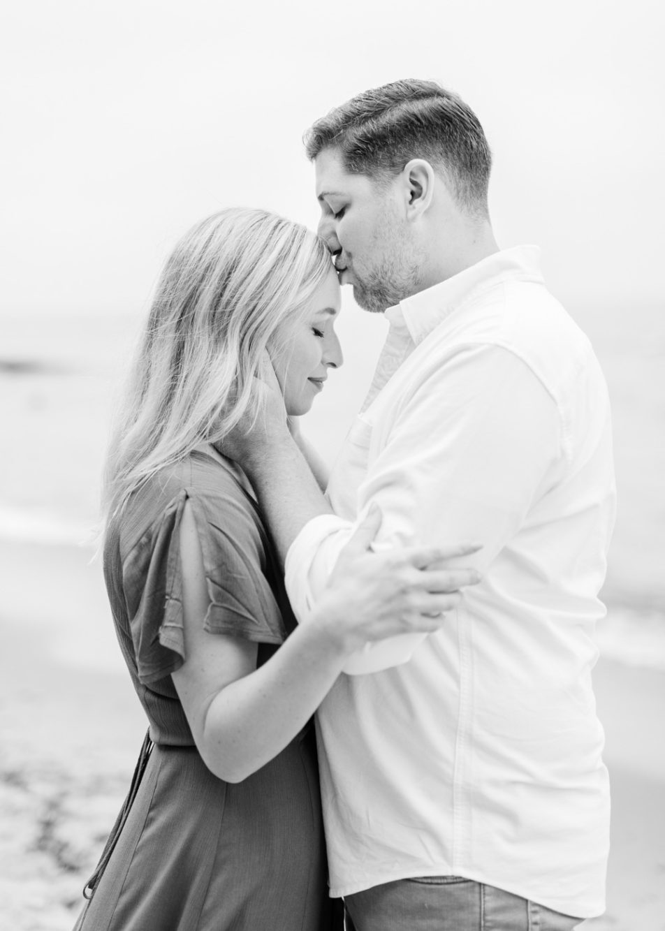 Couple kissing during their beach engagement session at Huntington Beach in Cleveland