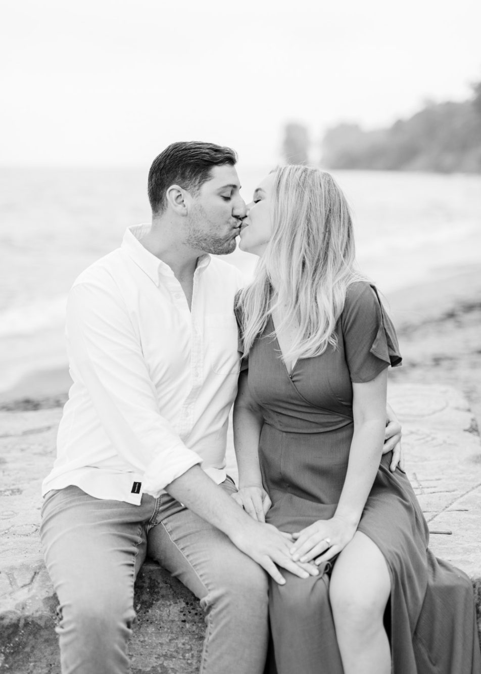 Engaged couple kissing at Huntington Beach on Lake Erie during their engagement session by Juliana Kaderbek Photography