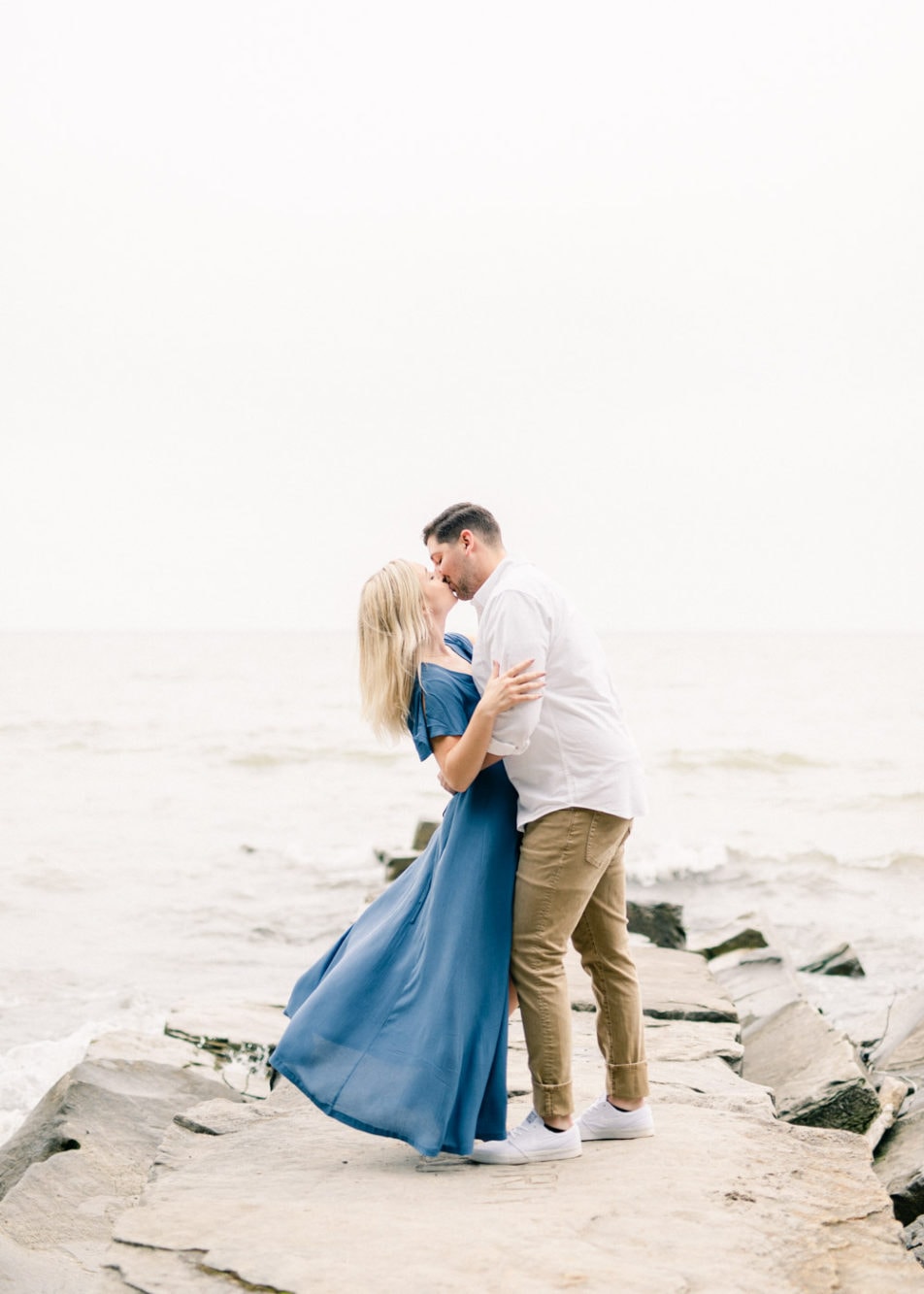 Engaged couple kissing on a pier at Huntington Beach on Lake Erie during their engagement session by Juliana Kaderbek Photography