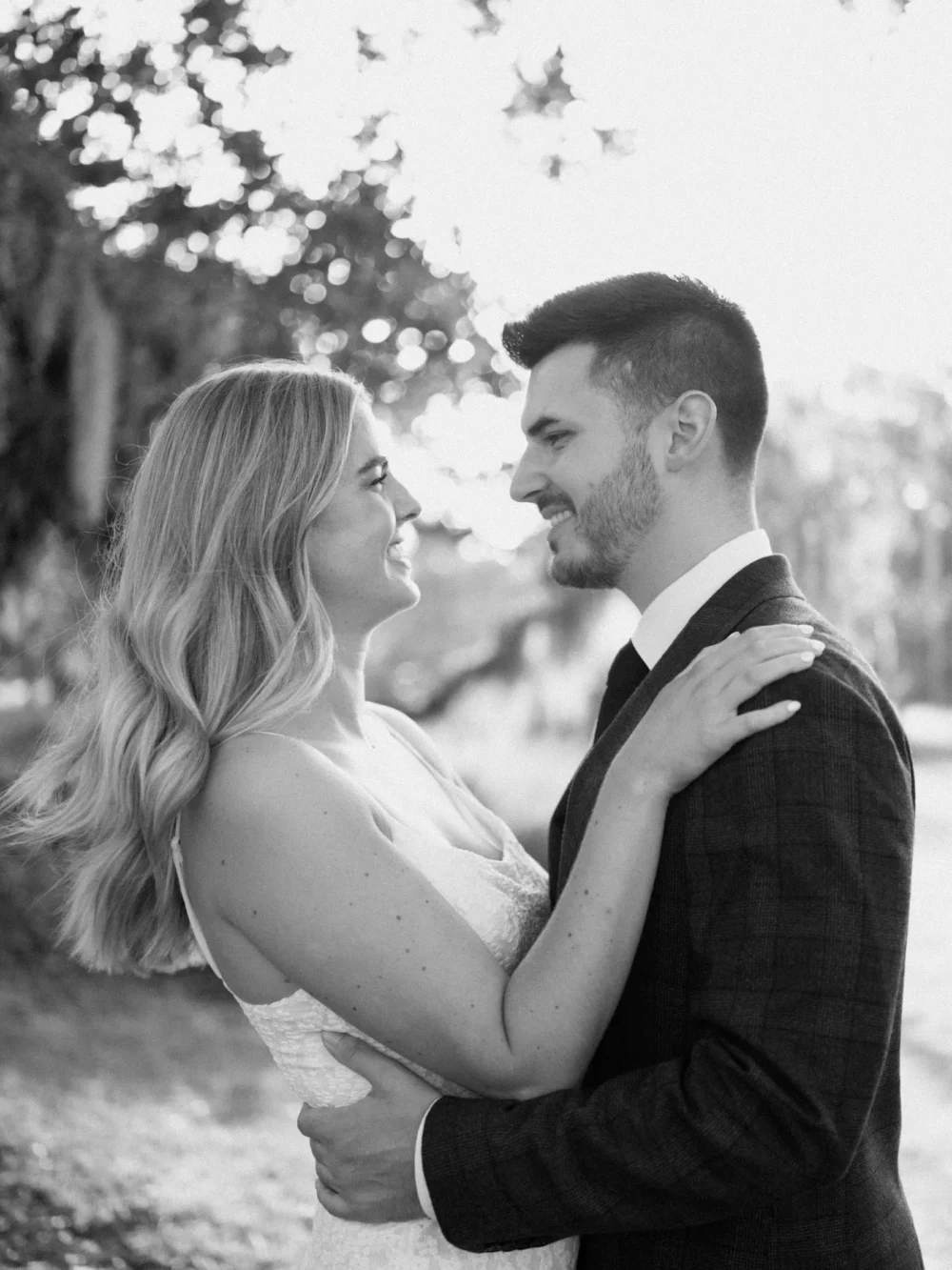 Bride and groom laughing, surrounded by moss covered trees during their engagement session in Charleston, SC