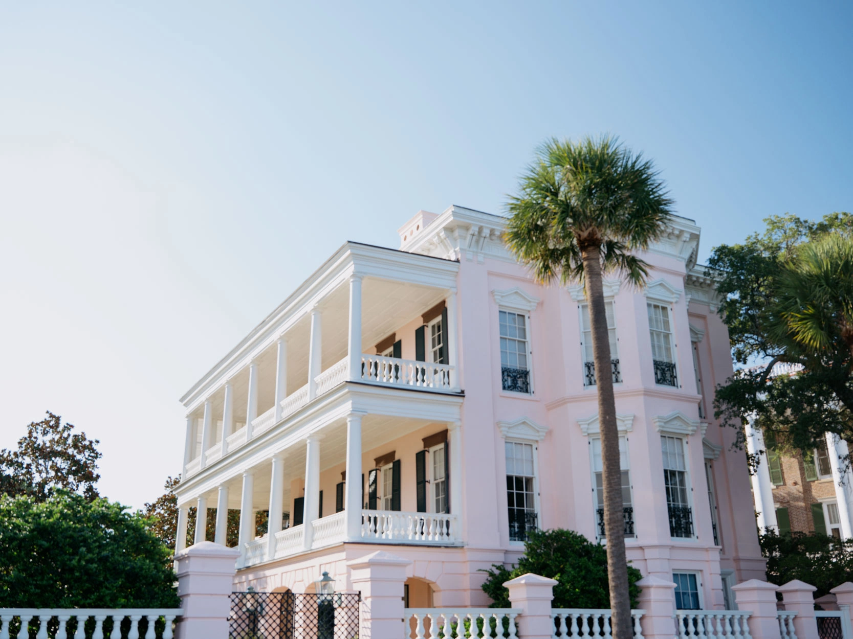 Pastel building in Charleston, Sc surrounded by palms.