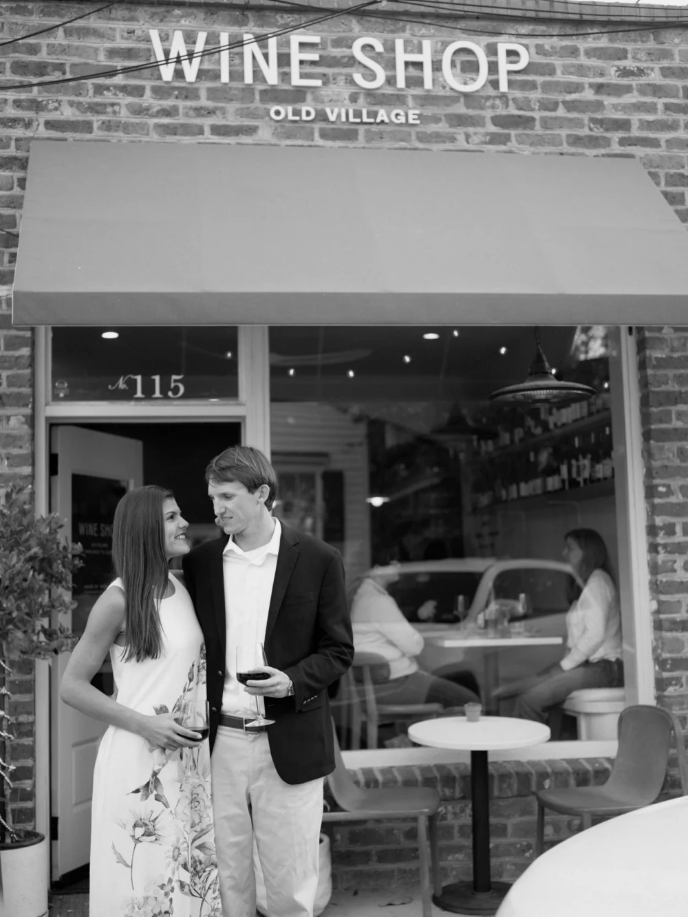 Engagement couple walking past the historic Wine Shop in Old Village Charleston